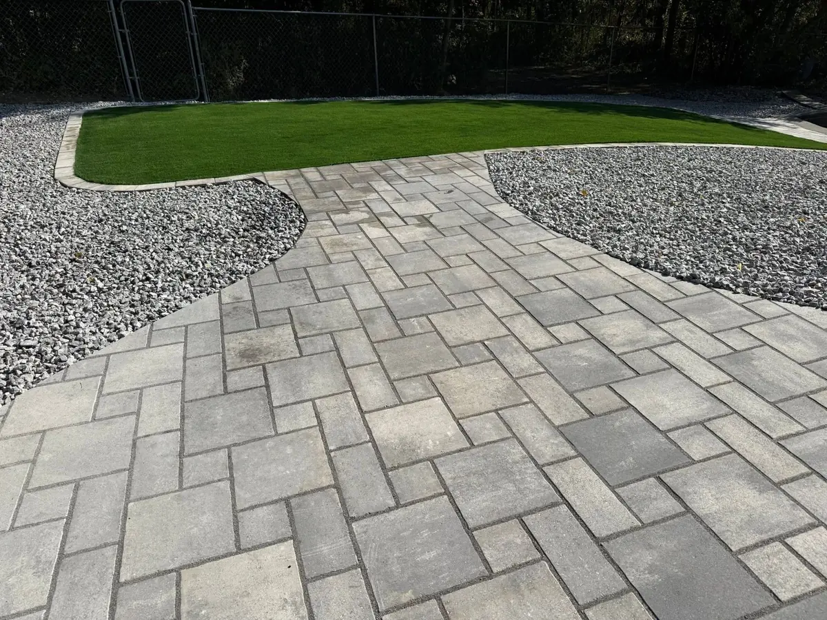 A herringbone paver walk curving between two rock beds